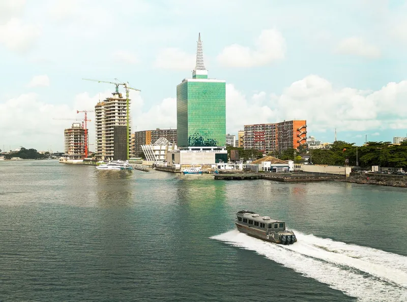 Aerial view of Lagos's Civic Centre Towers and Victoria Island waterfront, with a boat passing on the lagoon