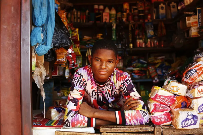A young shopkeeper standing at a market stall in Abuja, Nigeria