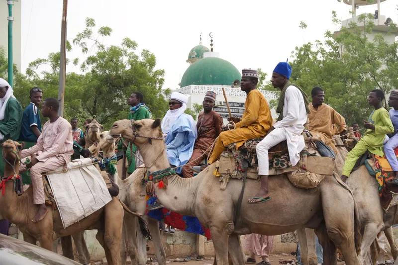 Traditional camel riders at a Sokoto festival, with the Sultan Muhammadu Bello mosque visible behind