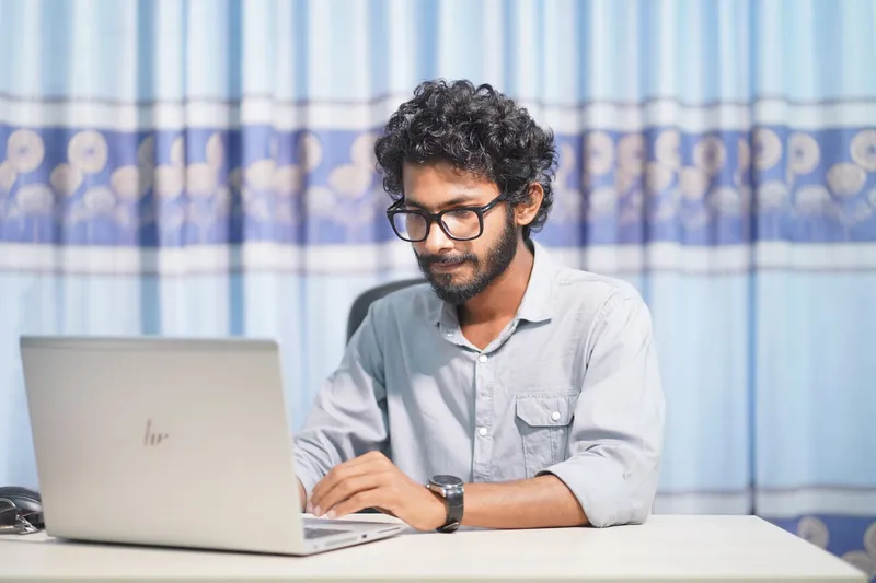 A web designer working on a laptop in a bright, minimalist room